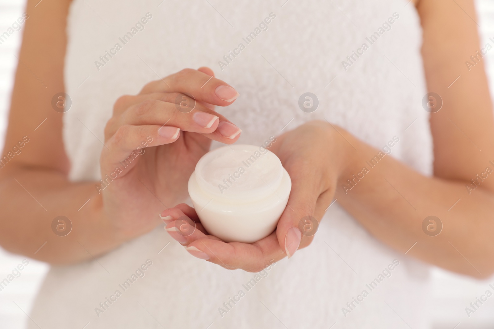 Photo of Woman holding jar with cream on light background, closeup