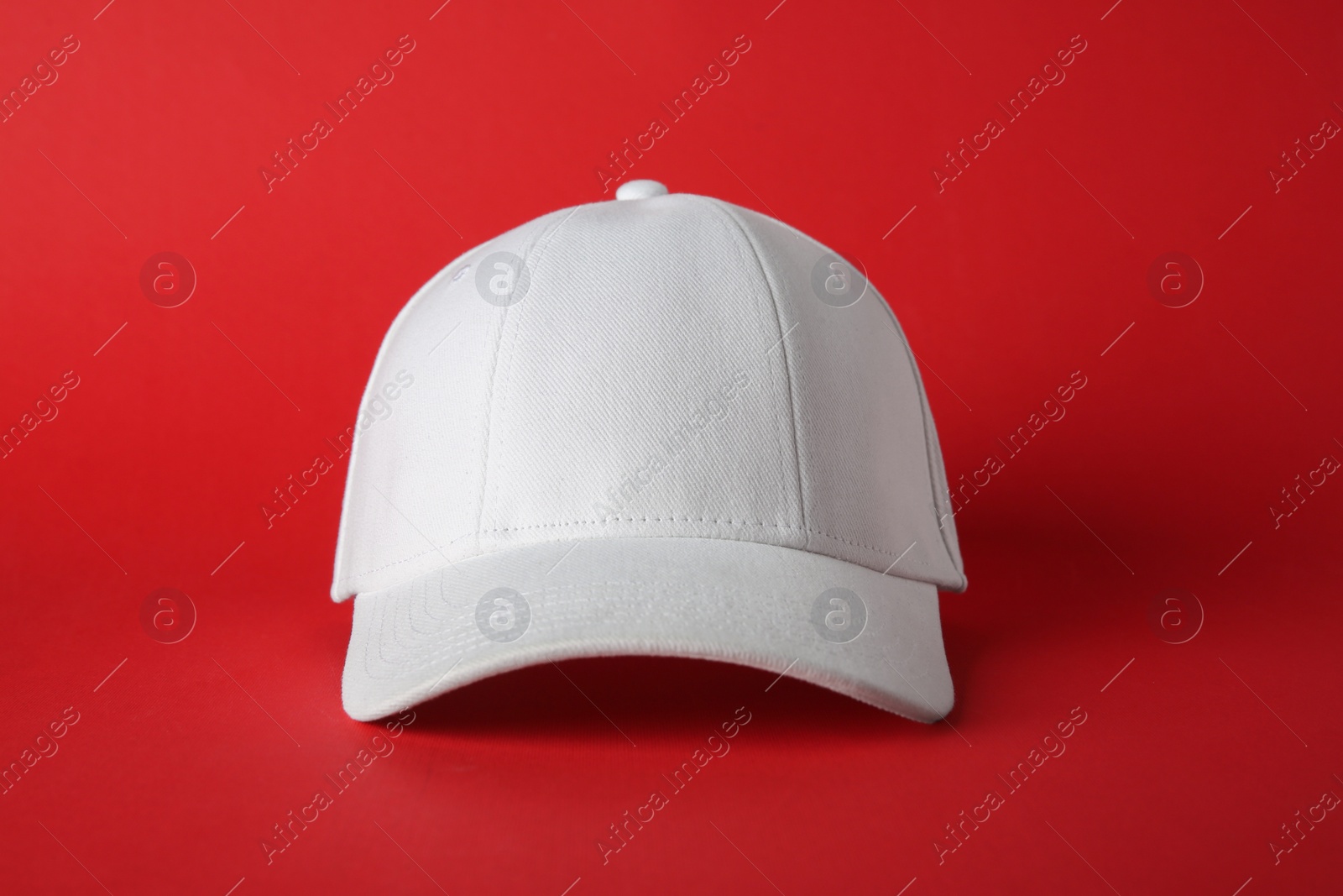 Photo of Stylish white baseball cap on red background