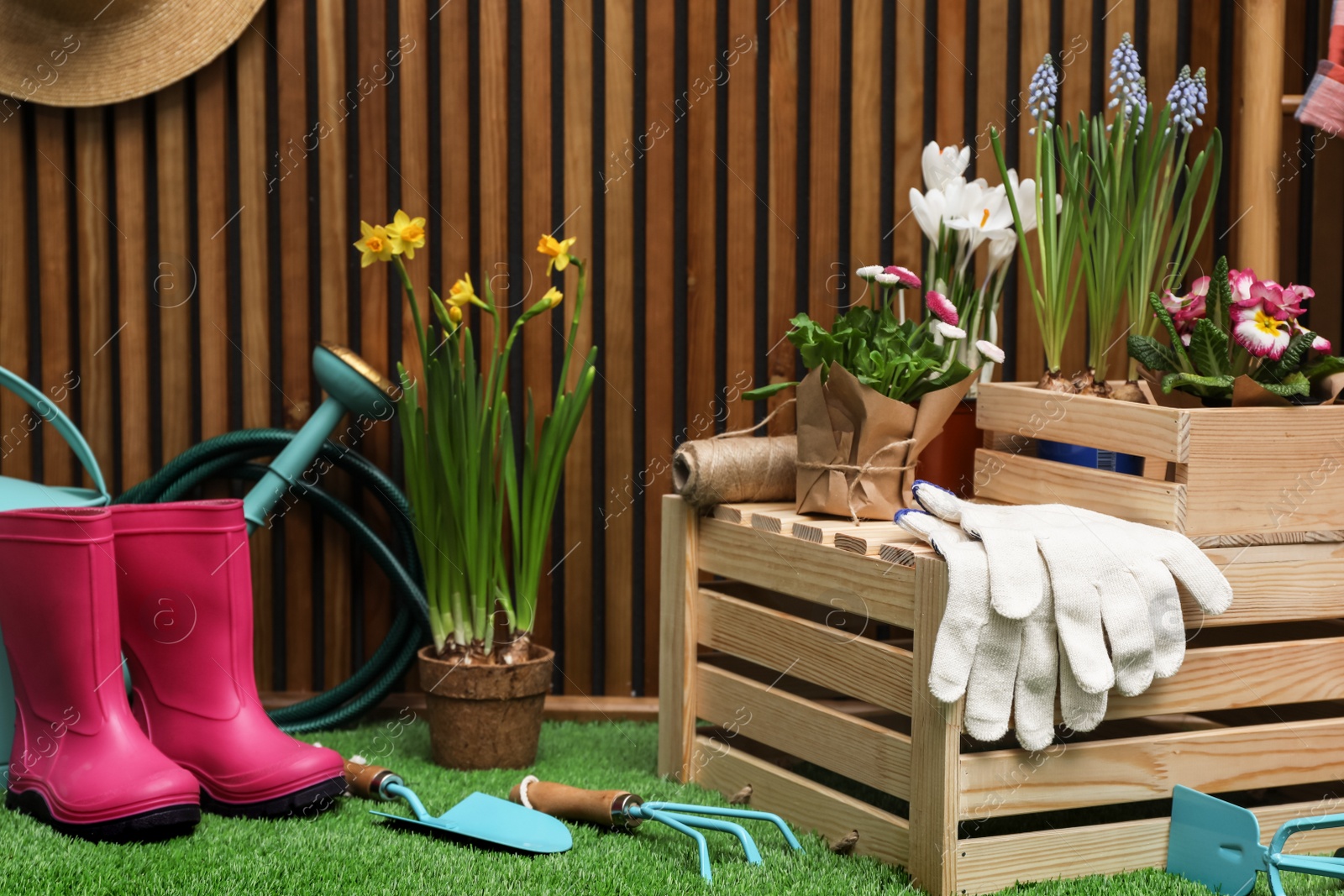 Photo of Composition with different gardening tools on artificial grass at wooden wall