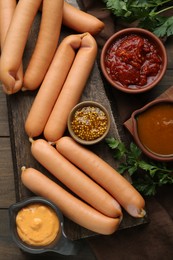 Delicious sausages, mustard, ketchup and parsley on wooden table, flat lay