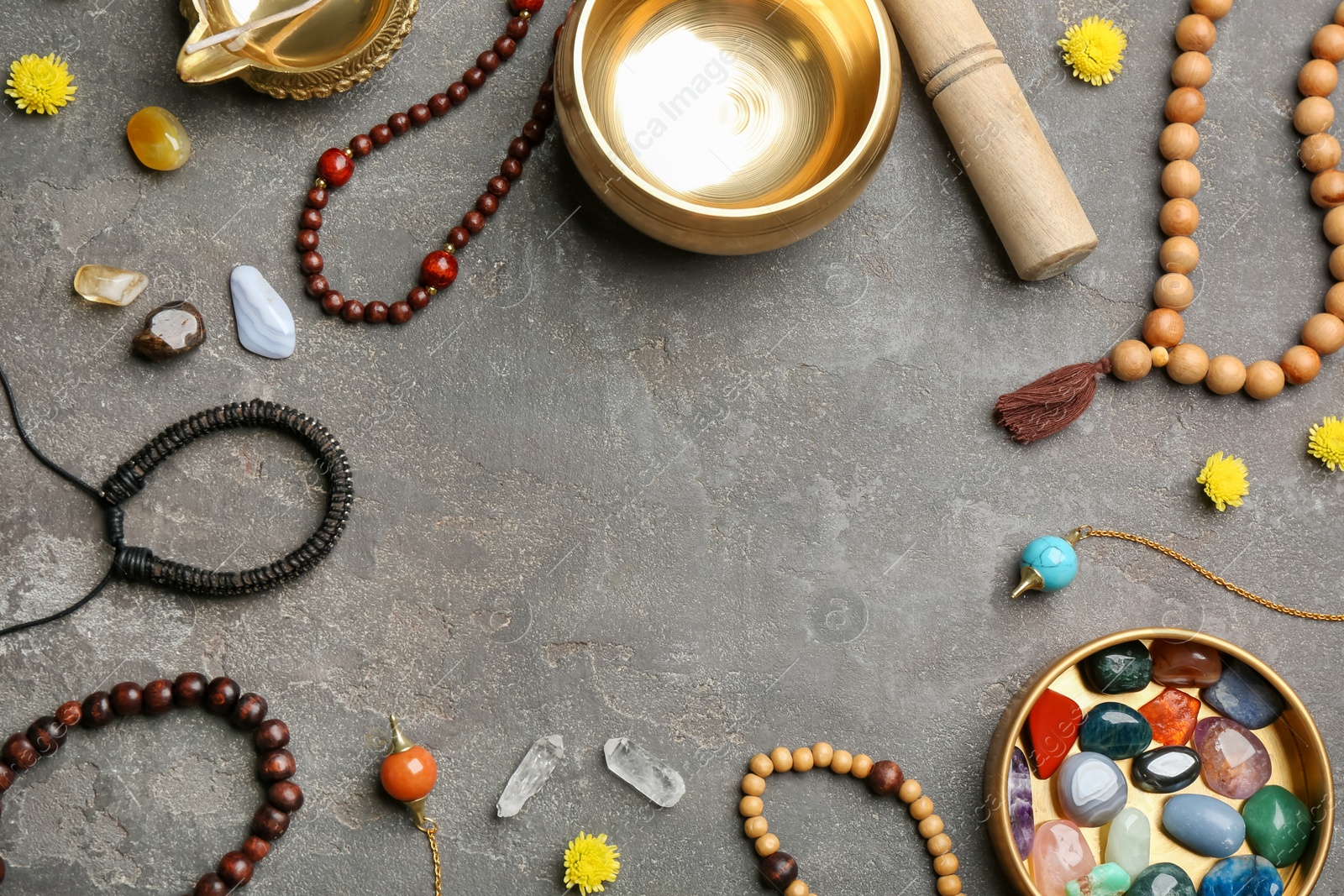 Photo of Frame of golden singing bowl and healing stones on grey table, flat lay with space for text