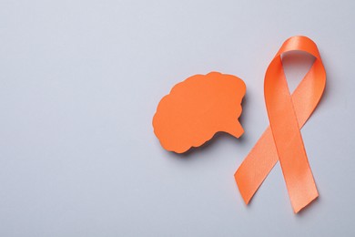 Photo of Orange ribbon and paper brain cutout on light grey background, flat lay with space for text. Multiple sclerosis awareness