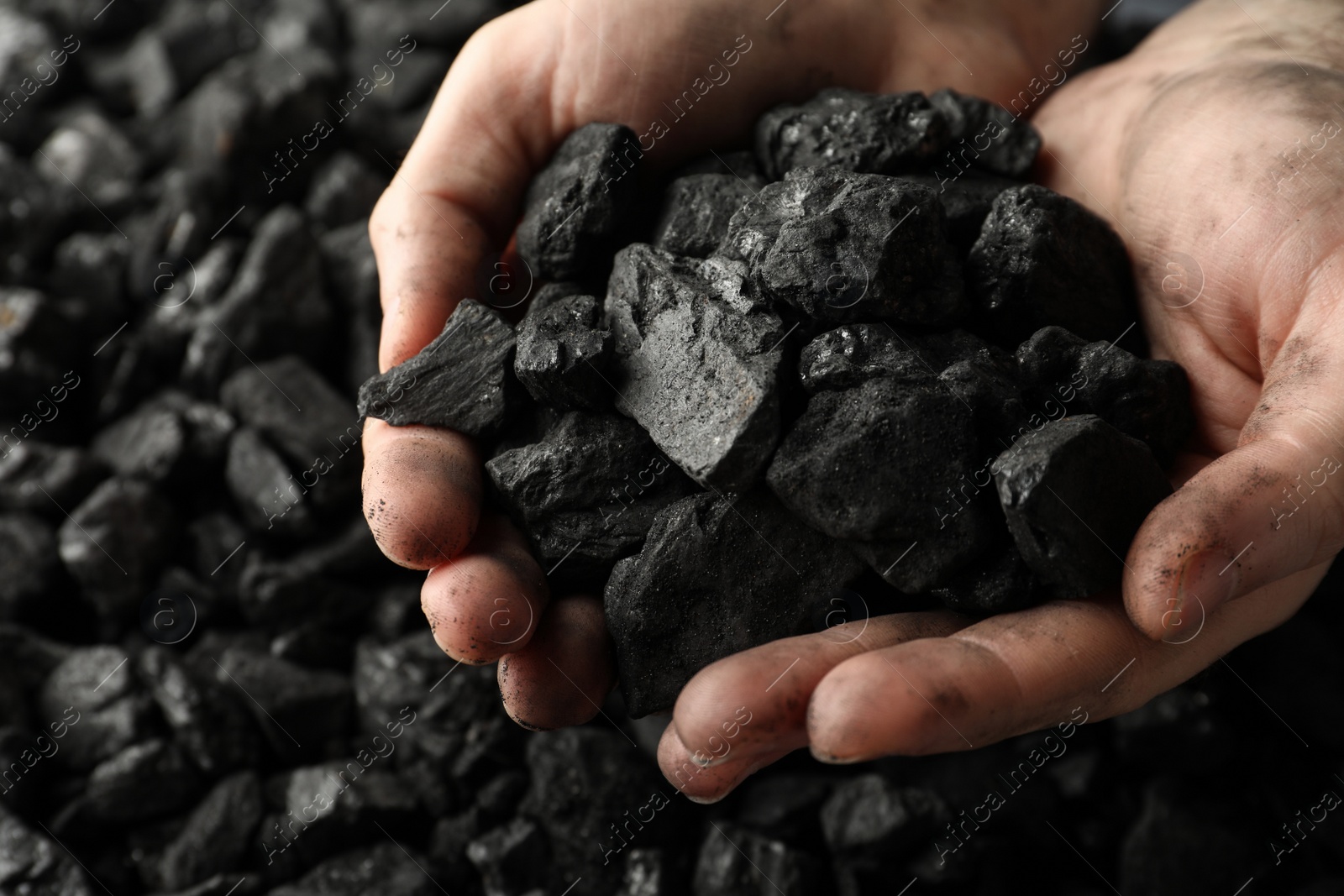 Photo of Man holding coal in hands over pile, closeup