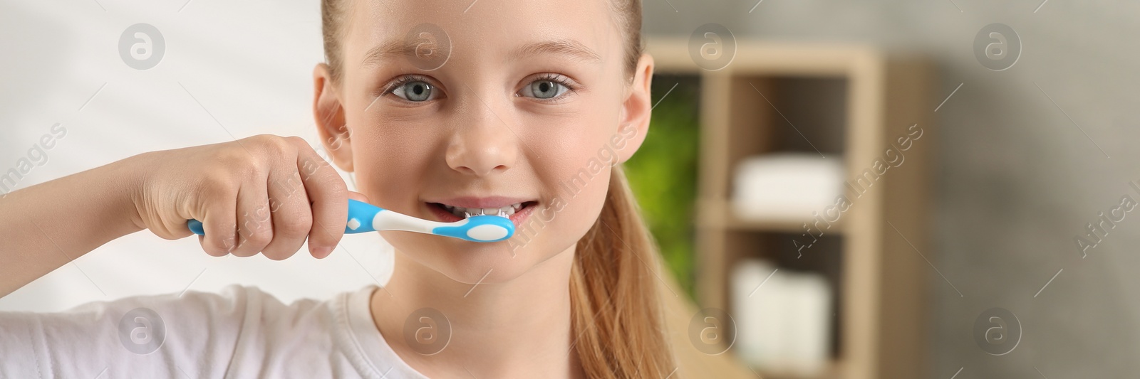 Image of Cute little girl brushing her teeth with plastic toothbrush in bathroom. Banner design with space for text