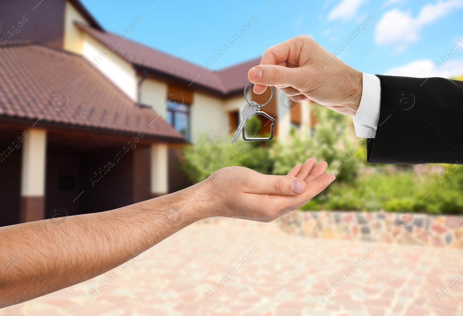 Image of Real estate agent giving key to man against house with garden, closeup