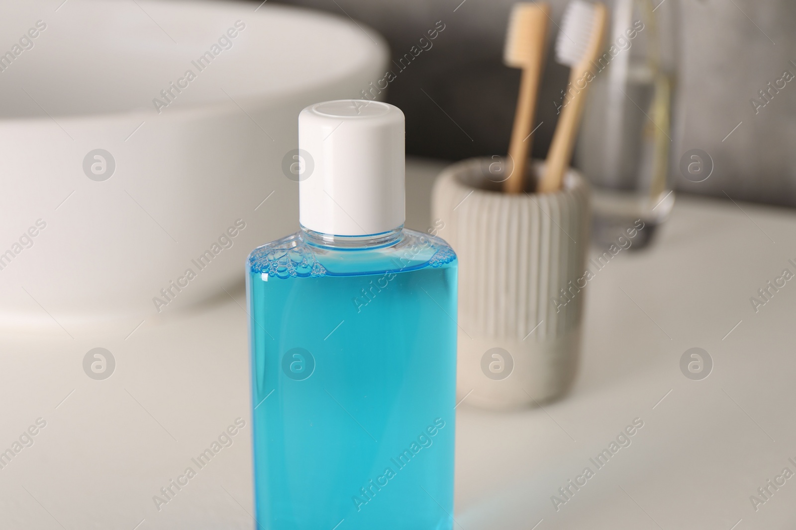 Photo of Bottle of mouthwash on white table in bathroom, closeup