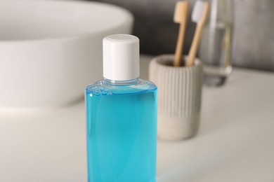 Bottle of mouthwash on white table in bathroom, closeup