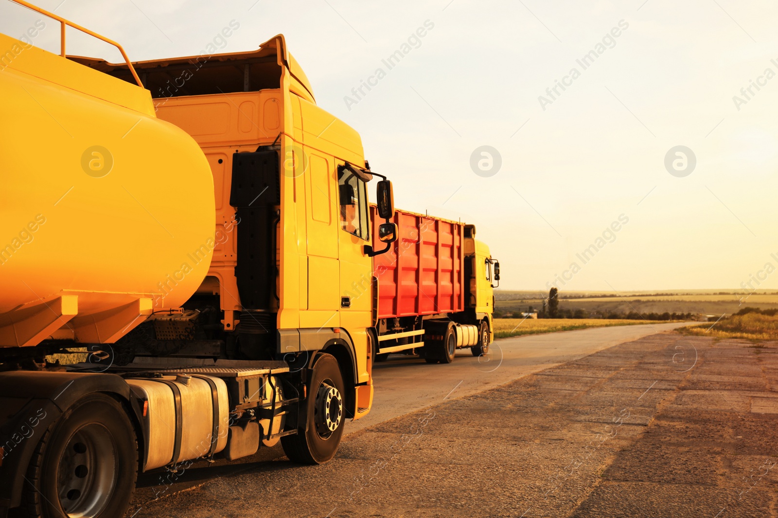 Photo of Modern bright trucks on country road. Space for text