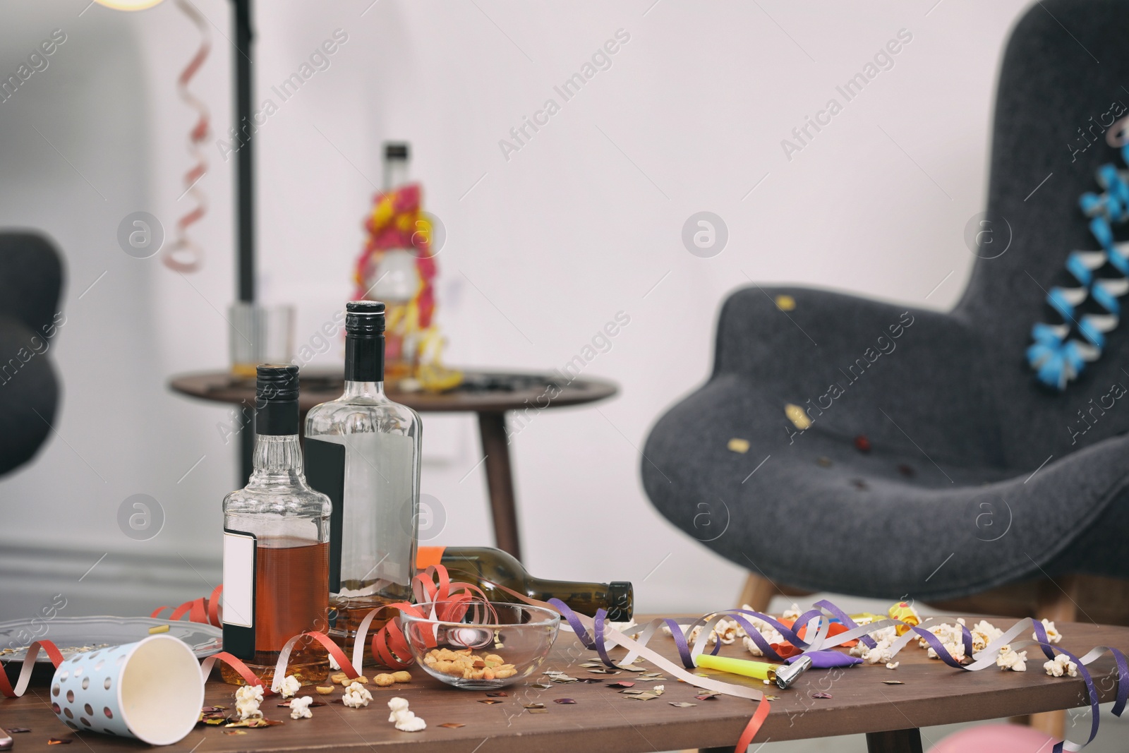 Photo of Messy table with popcorn and bottles after party indoors