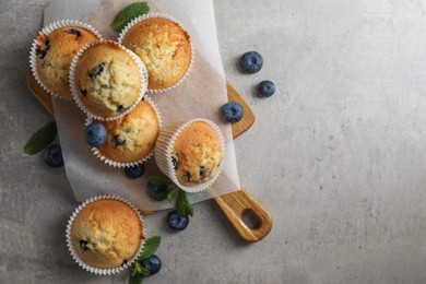 Photo of Delicious sweet muffins with blueberries and mint on grey table, flat lay. Space for text