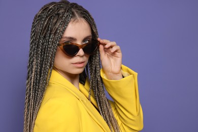 Photo of Beautiful woman with long african braids and sunglasses on purple background, space for text