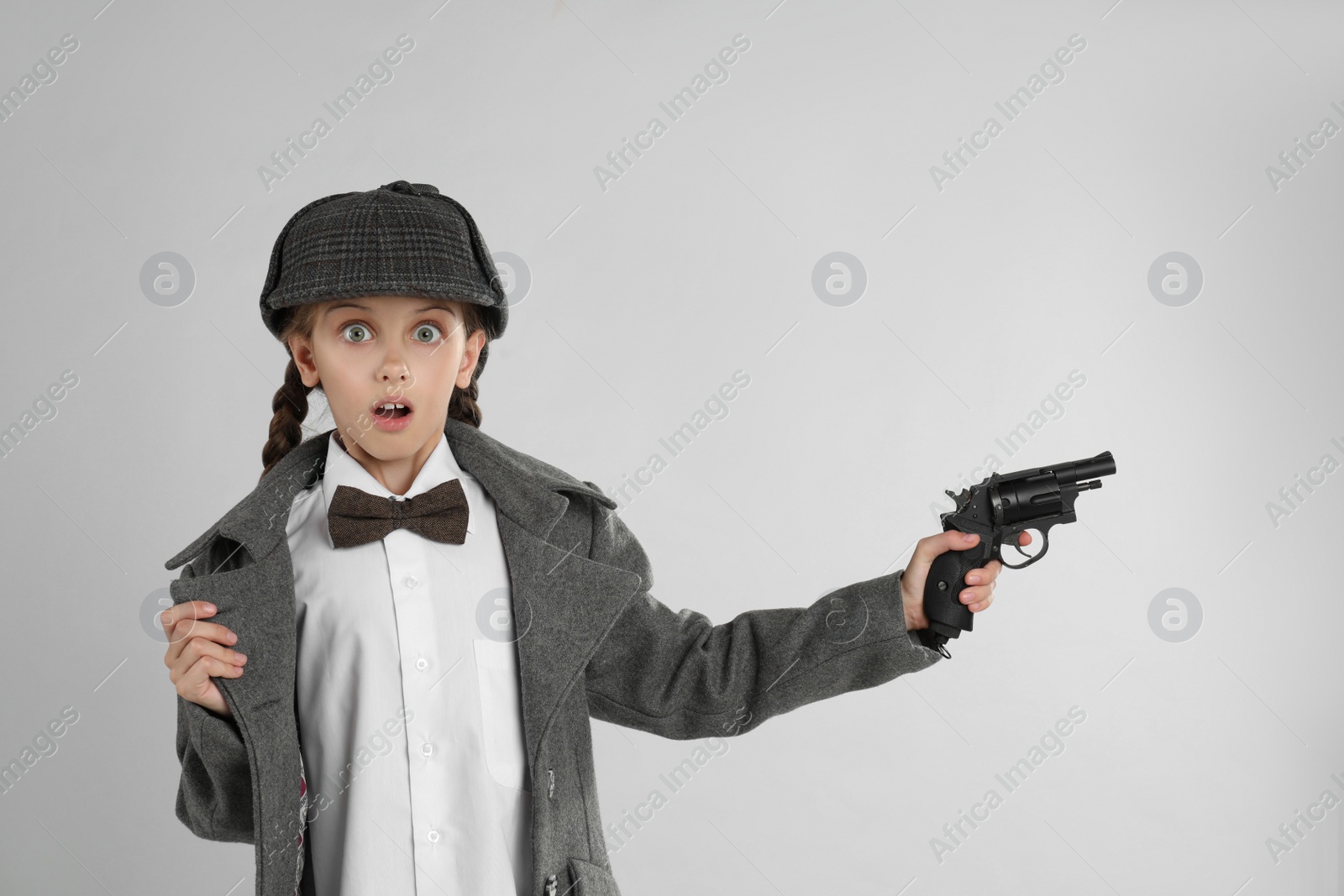 Photo of Cute little detective with revolver on grey background