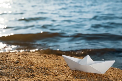 Photo of White paper boat near river on sunny day, space for text