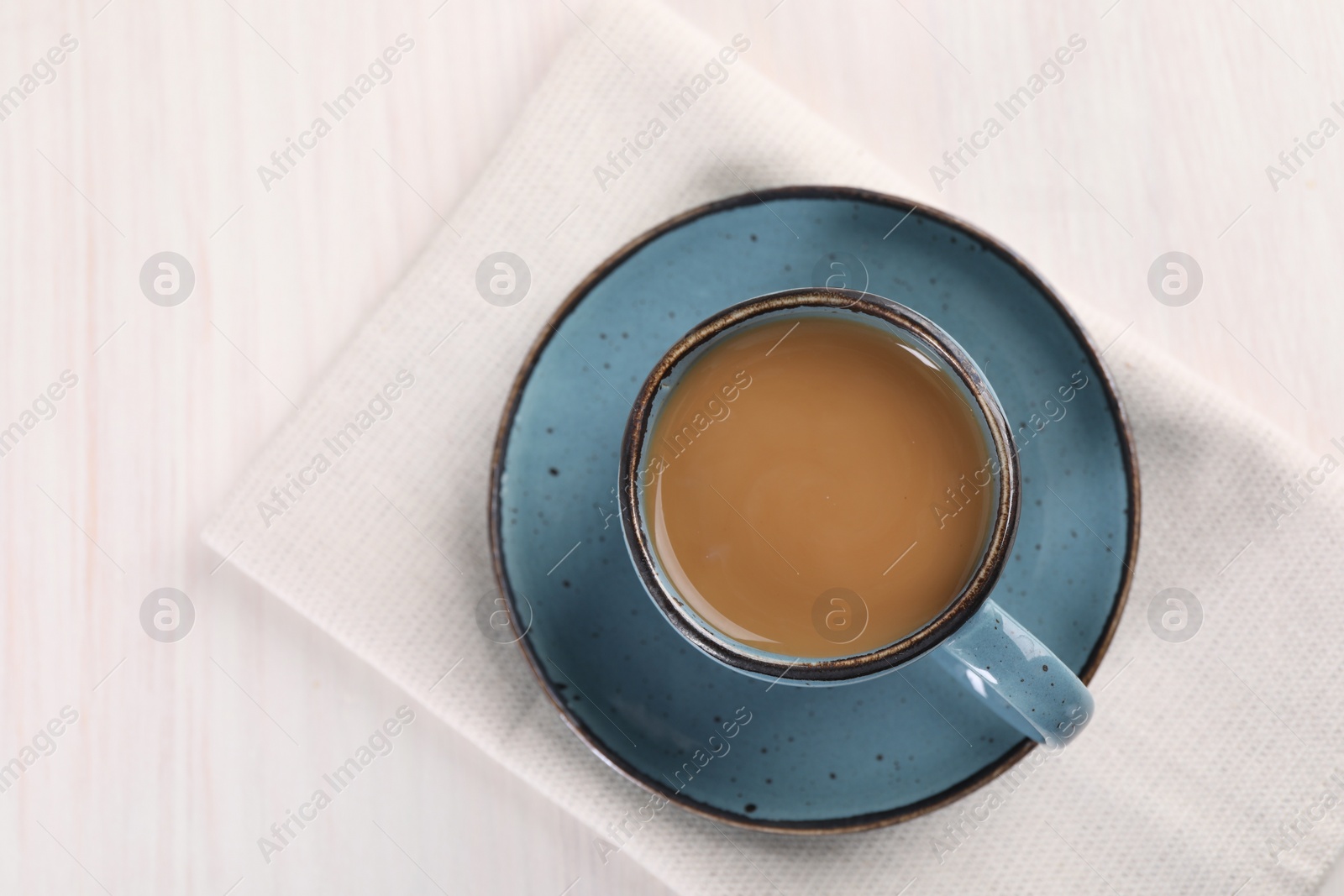 Photo of Delicious coffee in cup on white wooden table, top view. Space for text