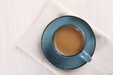 Photo of Delicious coffee in cup on white wooden table, top view. Space for text