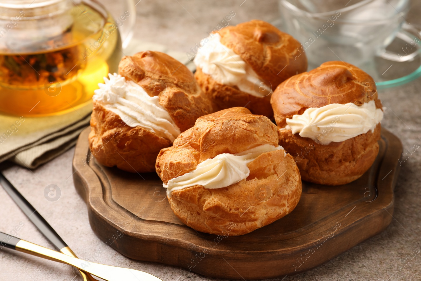 Photo of Delicious profiteroles filled with cream on grey table