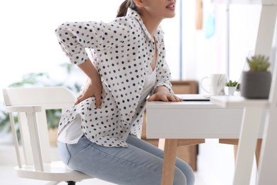 Photo of Woman suffering from back pain in office, closeup. Bad posture problem