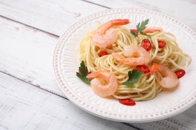 Tasty spaghetti with shrimps, chili pepper and parsley on wooden rustic table, closeup. Space for text