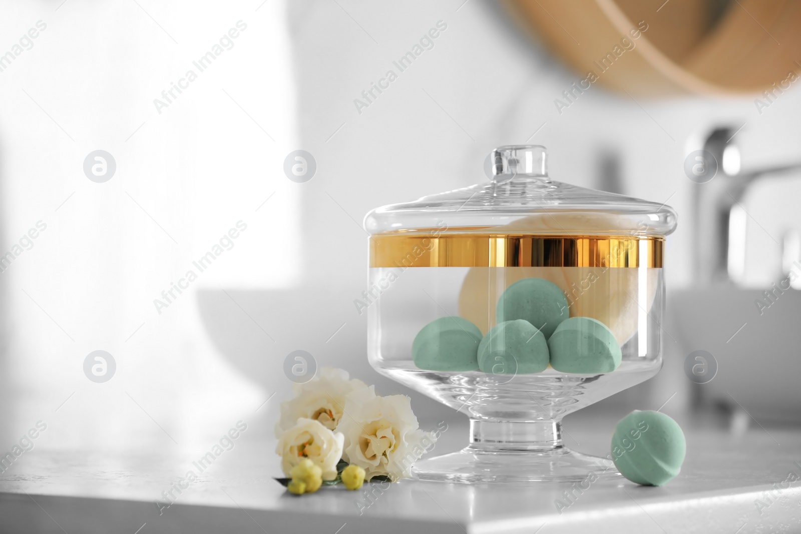 Photo of Jar with bath bombs and bath sponge on white countertop indoors