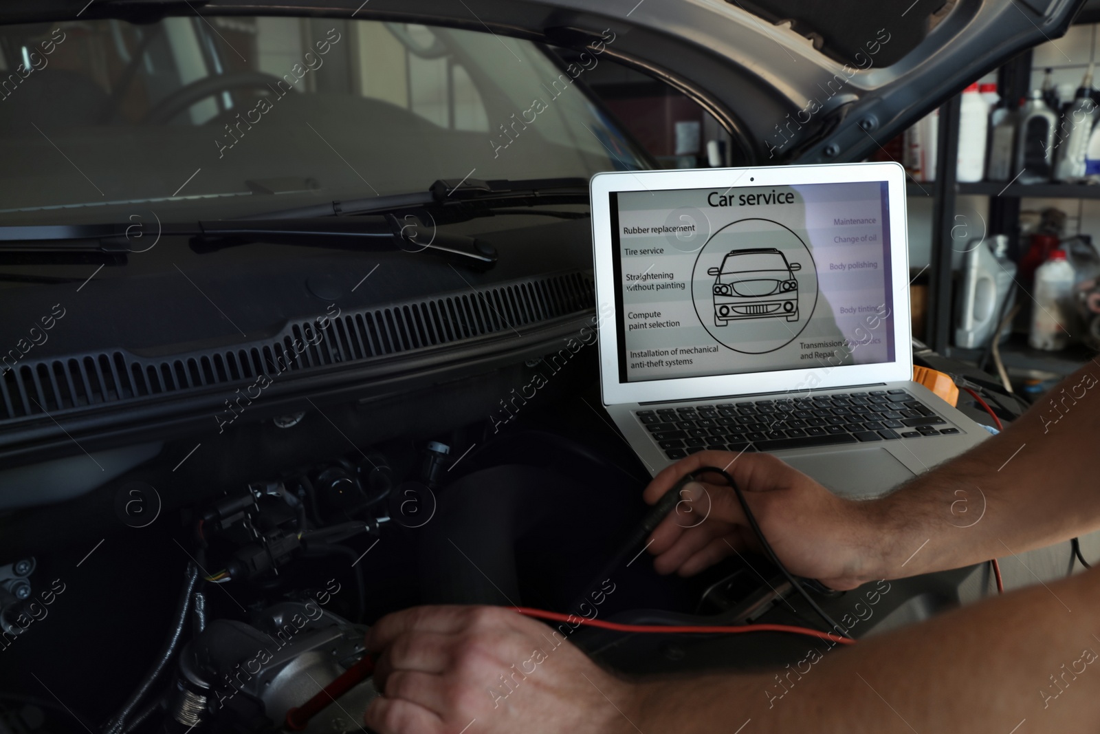 Photo of Mechanic with laptop doing car diagnostic at automobile repair shop, closeup