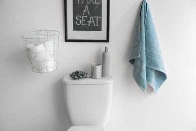 Decor elements, necessities and toilet bowl near white wall. Bathroom interior