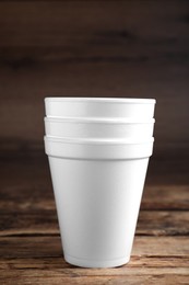 Photo of White styrofoam cups stacked on wooden table