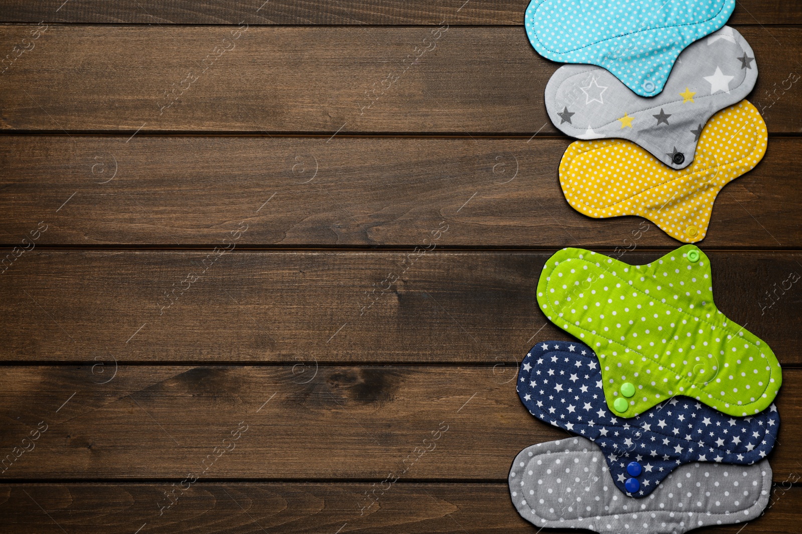 Photo of Many reusable cloth menstrual pads on wooden table, flat lay. Space for text