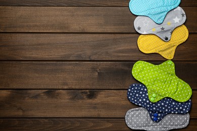 Many reusable cloth menstrual pads on wooden table, flat lay. Space for text