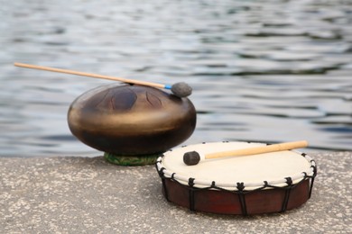 Photo of Different drums, soft mallet and drumstick near sea. Percussion musical instruments