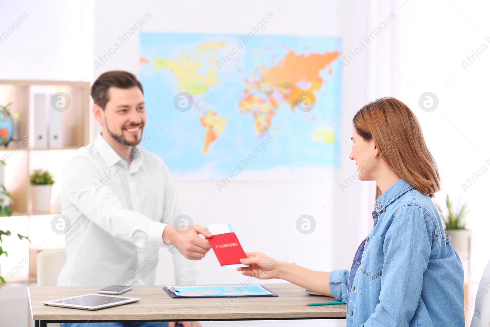 Photo of Male manager giving passport with ticket to client in travel agency