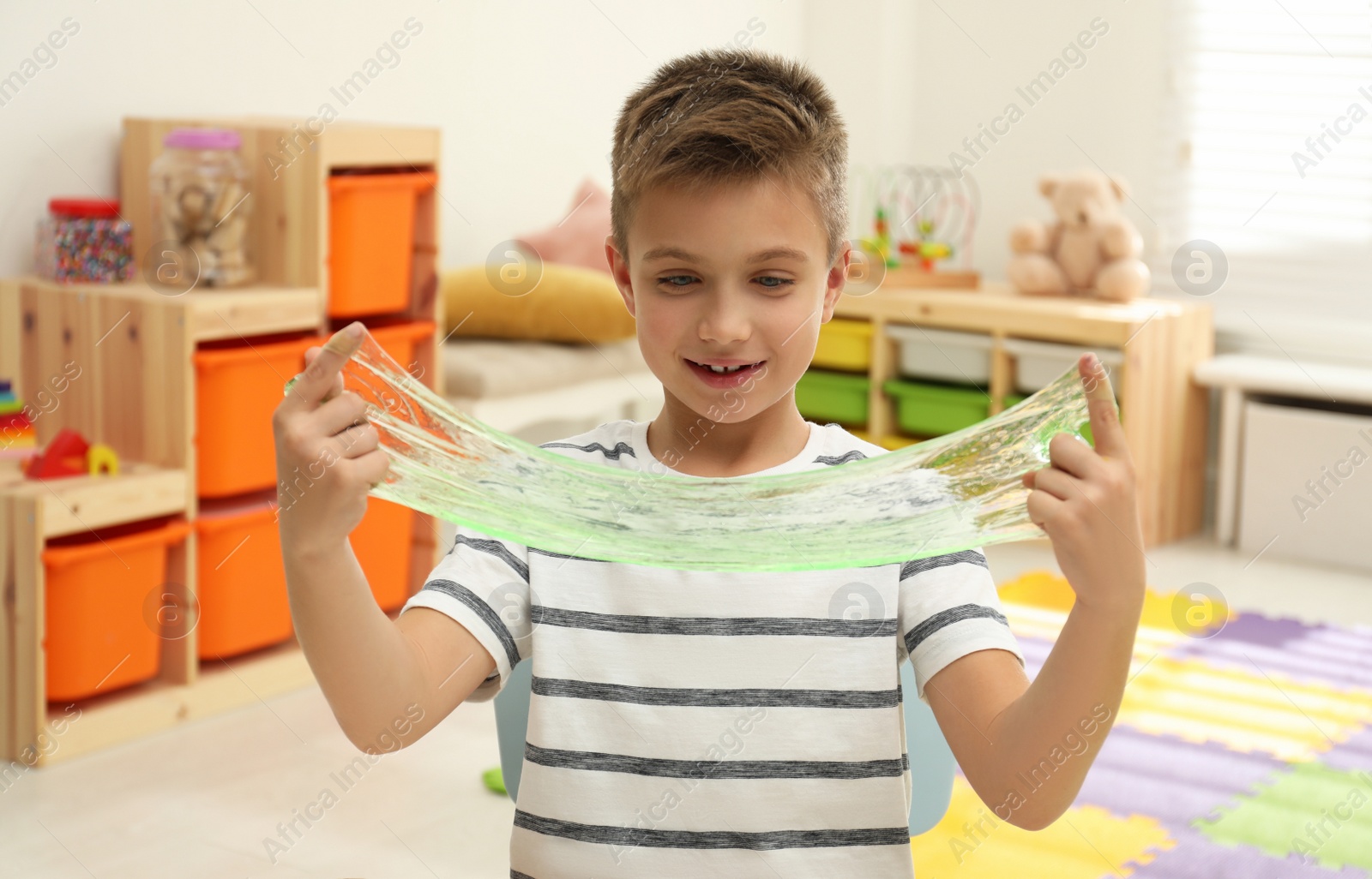 Photo of Little boy playing with slime in room