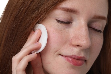 Photo of Beautiful woman with freckles wiping face on white background, closeup