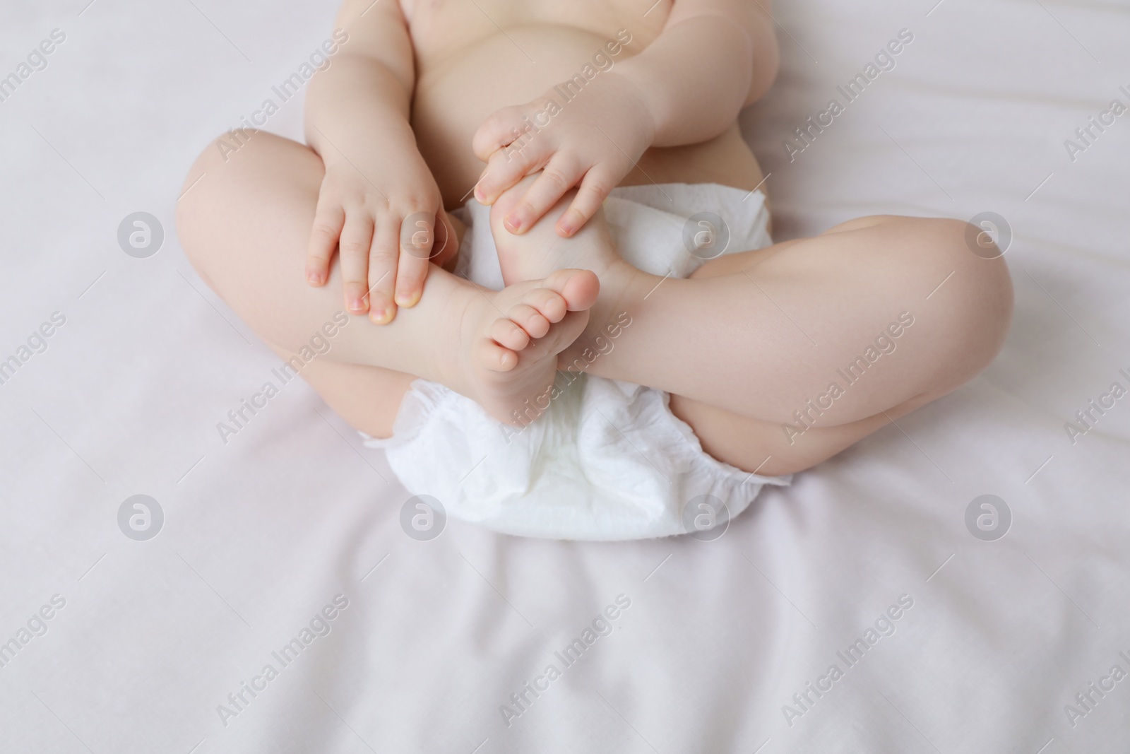 Photo of Little baby in diaper lying on bed, closeup