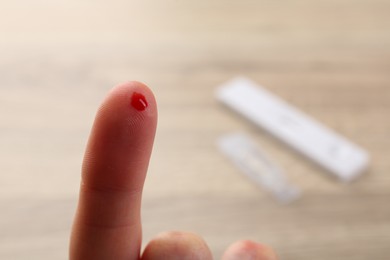 Photo of Laboratory testing. Woman with pricked finger and blood drop on blurred background, closeup. Space for text