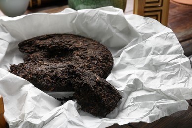 Photo of Broken disc shaped pu-erh tea on wooden table