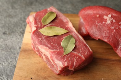 Photo of Pieces of raw beef meat and spices on grey table, closeup