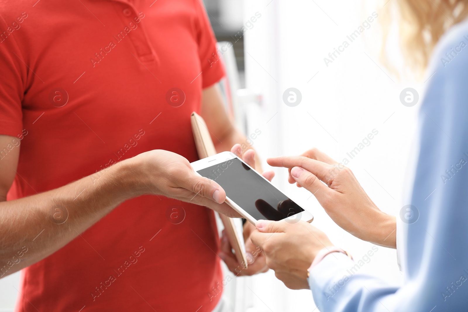 Photo of Woman using smartphone app to confirm receipt of envelope from courier, closeup