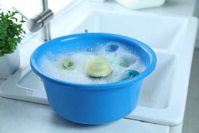Photo of Light blue basin with baby bottles on white countertop in kitchen