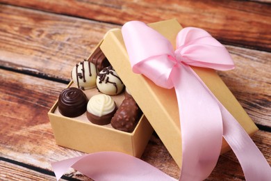 Photo of Box with tasty chocolate candies on wooden table, closeup