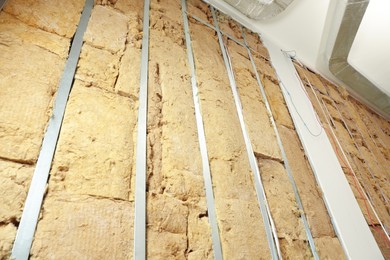 Wall with metal studs and insulation material indoors, low angle view