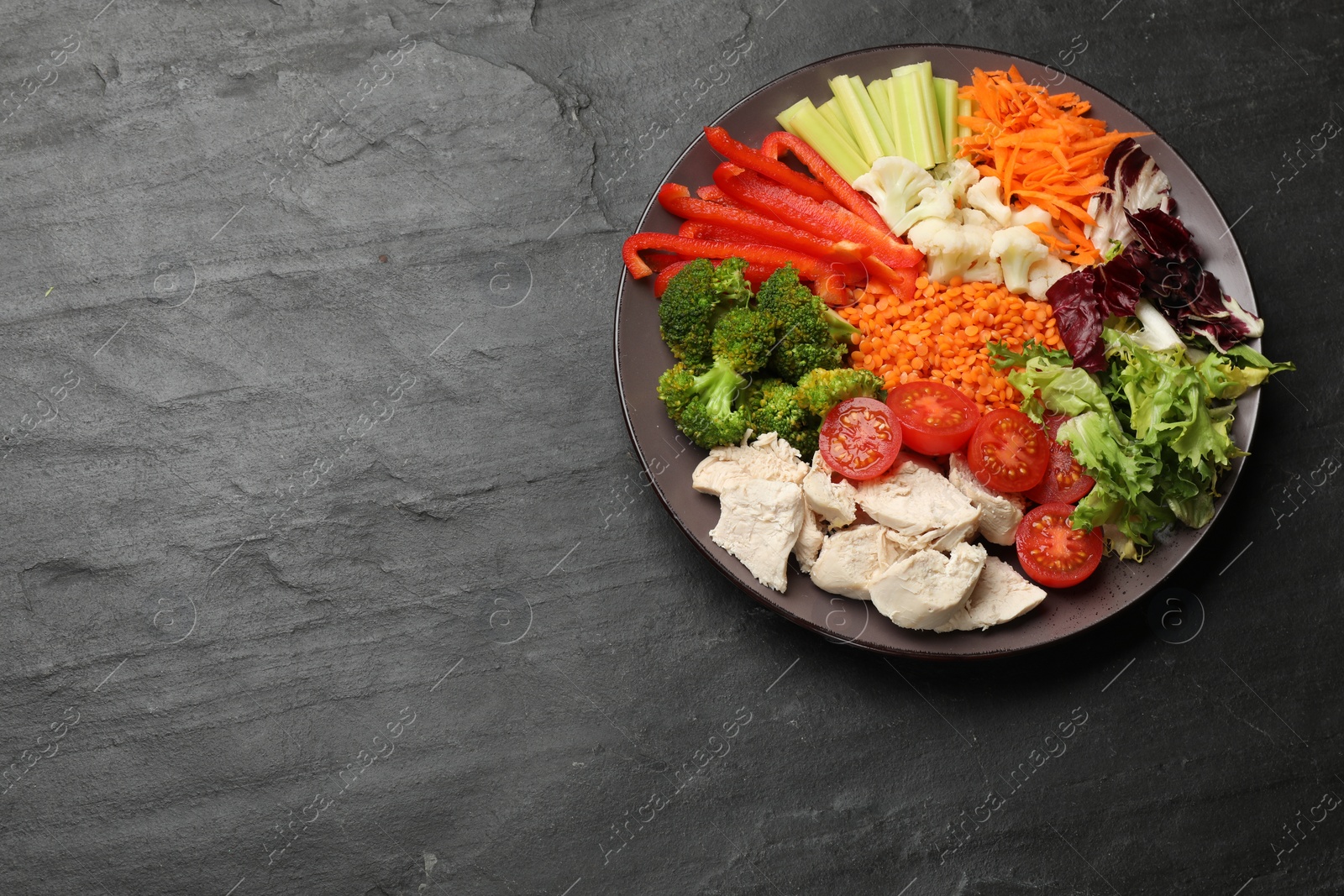 Photo of Balanced diet and healthy foods. Plate with different delicious products on black table, top view. Space for text