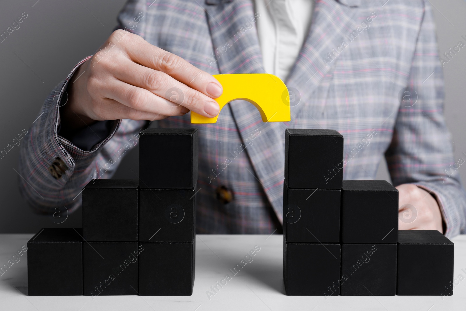 Photo of Businesswoman building bridge with colorful blocks at table, closeup. Connection, relationships and deal concept