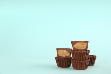 Photo of Sweet peanut butter cups on turquoise background. Space for text