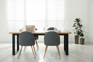 Photo of Conference room interior with glasses of water and laptop on wooden table