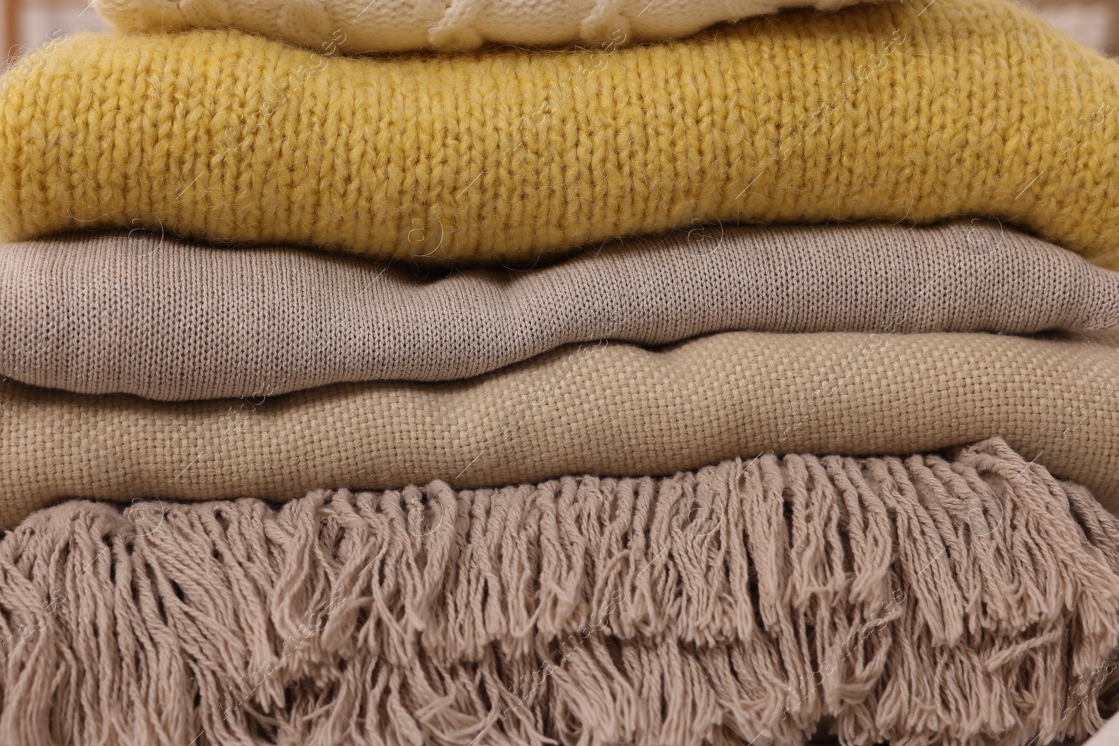 Photo of Stack of different folded blankets and clothes, closeup. Home textile