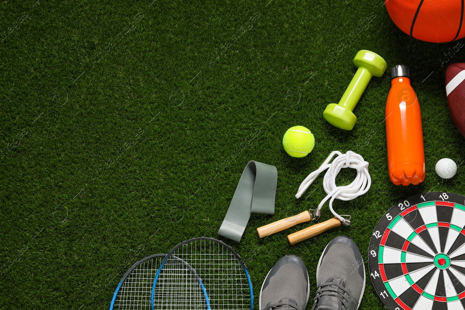 Photo of Different sports equipment on green grass, flat lay. Space for text