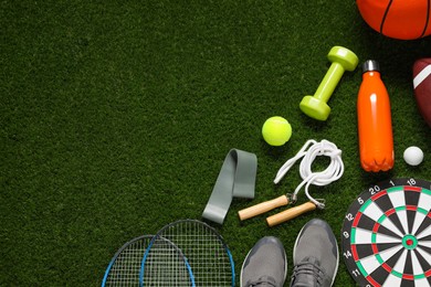 Photo of Different sports equipment on green grass, flat lay. Space for text