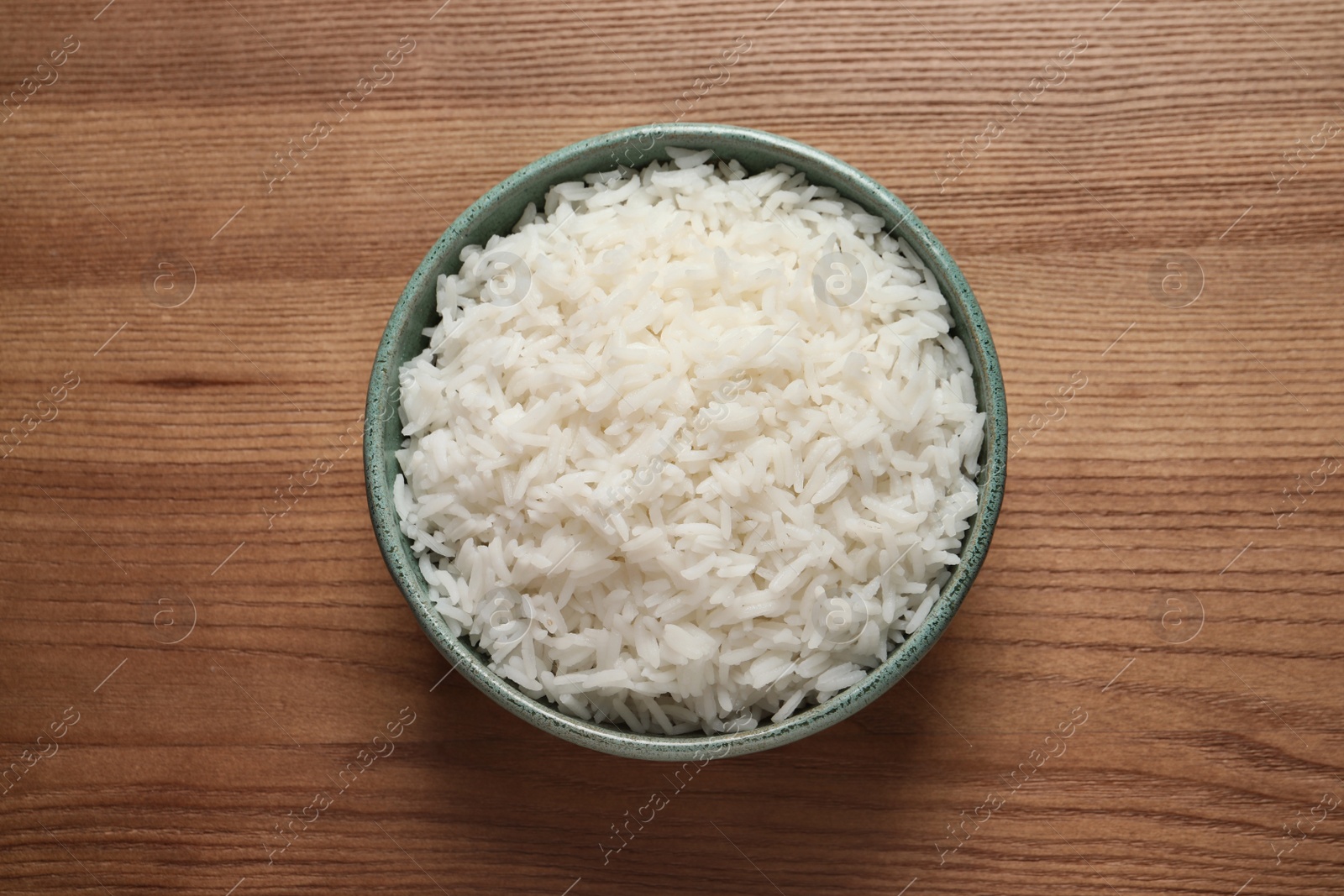 Photo of Bowl of cooked rice on wooden background, top view