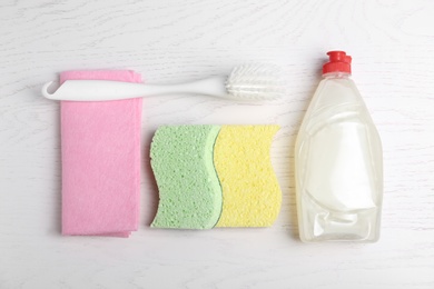 Cleaning supplies for dish washing on white wooden table, flat lay