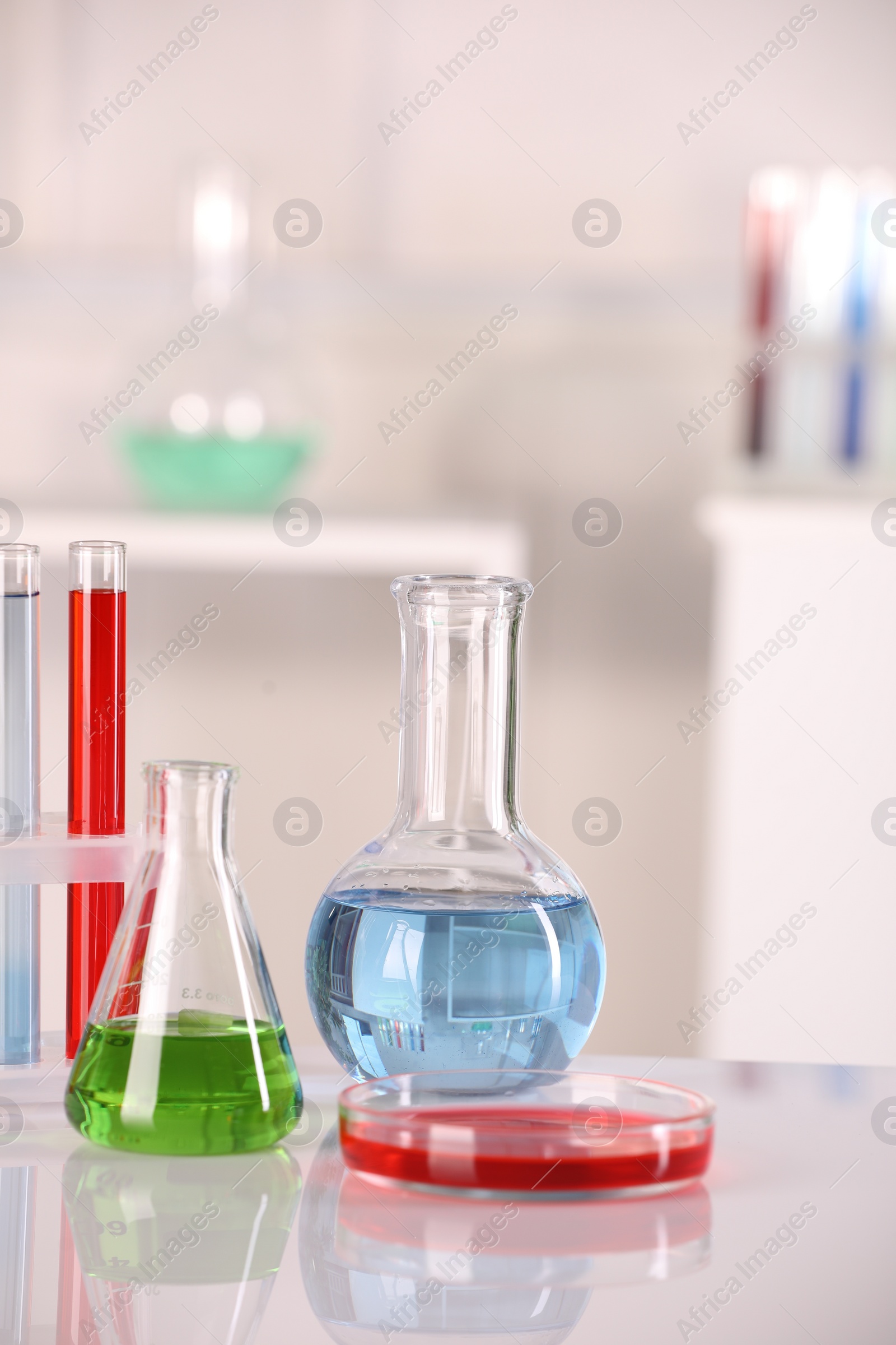 Photo of Laboratory analysis. Glass flasks, Petri dish and test tubes with liquids on white table against blurred background. Space for text